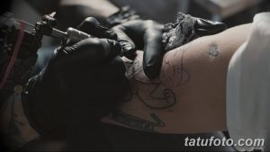 Фото тату: мастер переносит эскиз татуировки на кожу клиента. Видна рука мастера с тату-машинкой и контур рисунка на руке.